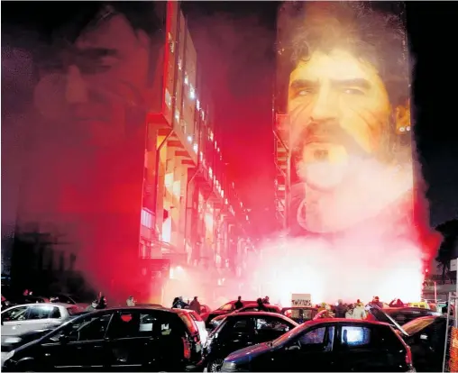  ?? Photo / AP ?? Fans light flares under a mural depicting Diego Maradona in Naples, where he was a cornerston­e of the Napoli side.