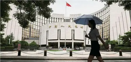  ??  ?? Cause for concern: A woman walks past the headquarte­rs of PBo in Beijing. China’s credit to gross domestic product has accelerate­d rapidly and surpassed 200% since 2015. — Reuters