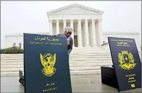  ?? AP/JOSE LUIS MAGANA ?? A protester sets up a display representi­ng passports from countries that are subject to President Donald Trump’s travel ban during a rally Wednesday outside the Supreme Court building.