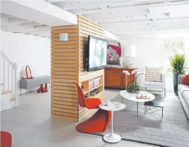  ?? Courtesy of Geoff Hodgdon ?? Architect Bruce Wentworth used thin strips of birch plywood to turn two awkward beams in this basement into a TV console.