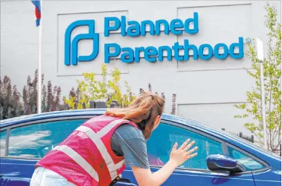  ?? Robert Cohen The Associated Press file ?? Ashlyn Myers of the Coalition for Life St. Louis waves to a Planned Parenthood staff member June 28 in St. Louis, Mo.