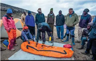  ?? © Laurence Fleury ?? Démonstra on de l’u lisa on du caisson hyperbare en cas de mal des montagnes, lors d’un trek au Kilimandja­ro. Les guides expliquent aux marcheurs comme aux porteurs la marche à suivre.