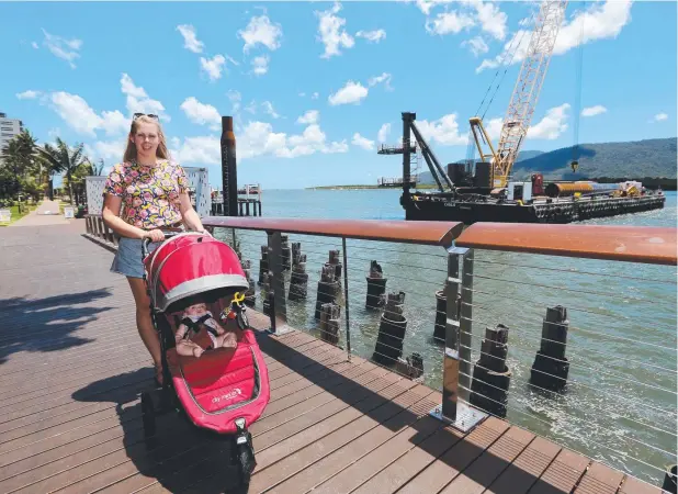  ?? Picture: STEWART MCLEAN ?? SHIP READY: Piling work has begun at the Cairns Port to extend the wharves. Ingrid Beatie walks her 6-month-old Harriet past one of the new piles.