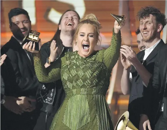  ?? PHOTO BY KEVORK DJANSEZIAN/GETTY IMAGES ?? British singer-songwriter Adele hoists one of her five trophies — or what’s left of it — at the Grammy Awards in Los Angeles on Sunday night.