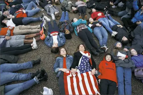  ?? Evan Vucci/Associated Press ?? Abby Spangler and her daughter Eleanor Spangler Neuchterle­in, 16, hold hands as they participat­e in a “lie-in” during a protest in favor of gun control reform in front of the White House on Monday in Washington.