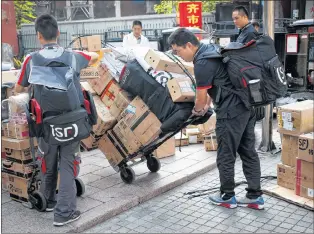  ?? AP PHOTO ?? Delivery workers pull carts loaded boxes of goods for their customers outside an office building in Beijing, Monday. China on Monday promised retaliatio­n if U.S. President Donald Trump escalates their tariff battle, raising the risk Beijing might target operations of American companies as it runs out of imports for penalties.