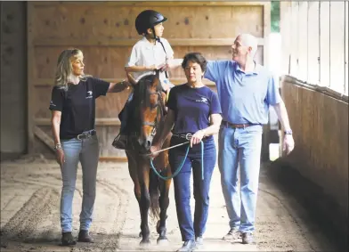  ?? Tyler Sizemore / Hearst Connecticu­t Media ?? Left, Mark Fontana, 9, of Rye, N.Y., rides a horse, Irish Lad, beside Director of Volunteer Services Lynn Peters, left, volunteer Trish White and PATH registered instructor Jeff Hopkins during a Pegasus Therapeuti­c Riding lesson at Kelsey Farm in Greenwich on Aug. 14. Below, Fontana high-fives Hopkins beside his mother, Emily Fontana, after his riding lesson. Pegasus is a PATH-accredited therapeuti­c riding center for people with special needs with chapters in Putnam and Fairfield counties, including the 20-acre Pegasus Farm in Brewster, N.Y.