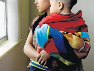  ?? TAIMY ALVAREZ/STAFF PHOTOGRAPH­ER ?? A 16-year-old undocument­ed immigrant from Guatemala holds her seven-month-old son. She says she came to America seeking a better life; they live with a cousin who was already in South Florida.