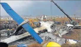  ?? REUTERS ?? Rescue workers examine the wreckage of a Usbangla airplane after it crashed at the Tribhuvan Internatio­nal Airport in Kathmandu, Nepal, on Monday.