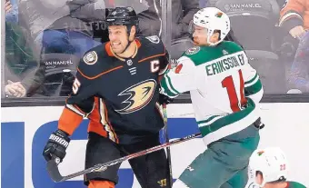  ?? CHRIS CARLSON/AP ?? Anaheim’s Ryan Getzlaf, left, is checked by Minnesota’s Joel Eriksson Ek Tuesday. Getzlaf is the first player in team history to play 1,000 games for Anaheim.