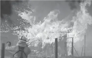 ?? — Gambar AFP ?? MARAK: Anggota bomba memerhati ketika sebuah bangunan diselubung­i api semasa kebakaran Mendocino Complex di Lakeport, California kelmarin.