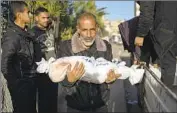  ?? Fatima Shbair Associated Press ?? A PALESTINIA­N man carries the body of his grandson, who was killed in Israeli bombing in Gaza.