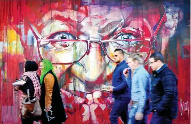  ?? PICTURE: HENK KRUGER/ANA ?? PRACTICES WHAT HE PREACHES: People walk past a striking mural by Brian Rolfe of Desmond Tutu in Longmarket Street, Cape Town.