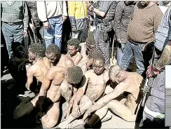  ?? (Pics: Reuters) ?? Police officers stand next to alleged illegal miners known as Zamazamas after they were rescued from residents who attacked them in reaction to the recent Krugersdor­p mass rape, in Krugersdor­p, a mining town in the West Rand, South Africa. (INSET) Neighbours try to put out the fire in the destroyed shack that was set alight by rampaging mobs of vigilantes.