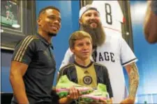  ?? SUBMITTED PHOTO ?? Union forward Charlie Davies, left, poses with artist Troy “Kickasso” Cole, right, and the cleats designed by 13-yearold Daniel Cooper for the team’s MLS Artwork event Friday.