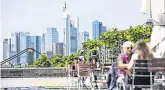  ??  ?? Germany stalling: People sit at a cafe terrace as skyscraper­s stand beyond on the city skyline in Frankfurt