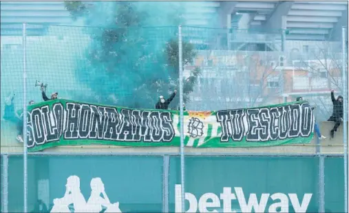  ??  ?? La pancarta y las bengalas verdiblanc­as con las que ultras béticos intentaron ayer animar a sus jugadores en la Ciudad Deportiva.