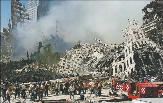  ?? (File Photo/AP/Beth A. Keiser) ?? Rescue workers continue their search Sept. 13, 2001, as smoke rises from the rubble of the World Trade Center in New York.