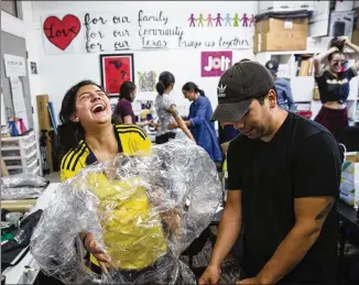  ?? AMANDA VOISARD / AMERICAN-STATESMAN ?? Daniela Rojas (left), 23, and Jason Choto, 26, prepare a tape body cast Tuesday that will be used as part of an art installati­on that participan­ts in the Art Caravan for the Children will place on the border fence this weekend at Alice Wilson Hope Park...