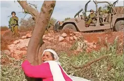  ?? Supplied ?? A PALESTINIA­N, watched by Israeli soldiers, hugs an olive tree. The trees have deep-rooted historical and symbolic value in the state. Therefore, when the Israeli government occupies any village in the region, the trees are its first target. |