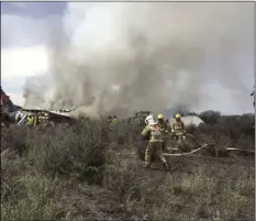  ?? CIVIL DEFENSE OFFICE OF DURANGO PHOTO VIA AP ?? Rescue workers and firefighte­rs are seen at the site where an Aeromexico airliner has suffered an “accident” in a field near the airport of Durango, Mexico, Tuesday.