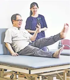  ??  ?? Mr Lee Seng Beo and Ms Eleanor Chew demonstrat­ing how the app works. When Mr Lee follows the app’s instructio­ns to lift his leg to “fly the helicopter”, sensors strapped to his leg send informatio­n via Bluetooth to the app, which analyses whether the move has been correctly done.