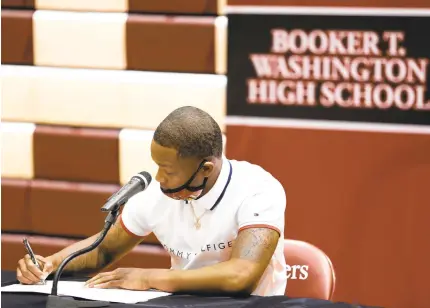  ?? STEPHEN M KATZ/STAFF ?? Booker T. Washington’s Rodney Hammond signs his letter of intent Wednesday to play for the University of Pittsburgh.