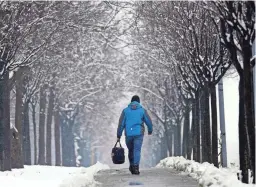  ?? DARKO VOJINOVIC/AP ?? A man walks through a snow covered street in Belgrade, Serbia, Sunday. Serbia and the rest of the region were hit by sudden rain and snow.