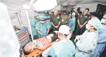  ??  ?? Sultan Nazrin (second left) watches a demonstrat­ion on life-saving surgery on an ‘injured’ soldier. — Bernama photo