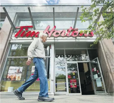  ?? ARLEN REDEKOP/PNG ?? A man walks past the Tim Hortons on West Broadway near Laurel. Witnesses say Ted, whose last name isn’t known, may have been slumped at his table, unresponsi­ve, for several hours before he was noticed last week.