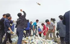  ?? AFP ?? Bottles containing rice, money and USB sticks are thrown into the sea by North Korean defector activists on Ganghwa island, west of Seoul, yesterday.