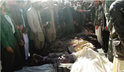  ??  ?? GHOR: Afghan men gather around the bodies of civilians, including children who were killed by Islamic State militants in Ghor province yesterday. — AFP