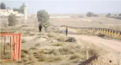  ??  ?? This photo taken on Feb 10, 2017 shows Iraqis walking next to the Iraq-Kuwait border barrier near the town of Umm Qasr.