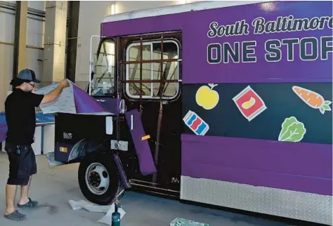  ?? BARBARA HADDOCK TAYLOR/BALTIMORE SUN ?? Oliver Cruz of Zurc Designs wraps a “candy truck,” a mobile convenienc­e store, in a garage at Baltimore Peninsula. This new candy truck will be part of South Baltimore One Stop.