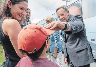  ?? PAUL CHIASSON THE CANADIAN PRESS ?? Coalition Avenir Quebec Leader Francois Legault greets Benjamin Menard as his mother Maryse Caron looks on during a campaign stop in Sherbrooke, Que., on Monday.