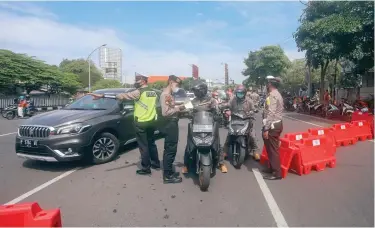  ?? ALLEX QOMARULLA/JAWA POS ?? TEKAN PERGERAKAN: Polisi menyeleksi pengendara di bundaran Taman Pelangi yang akan masuk Jalan A. Yani.