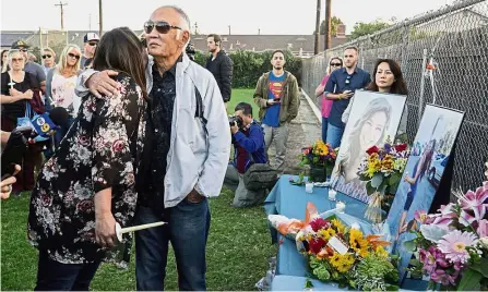  ??  ?? Profound loss: Kimura’s father, Haven (centre) hugging Tracy Gyurina after she showed him the photo display of his daughter at a candleligh­t vigil in Placentia. — AP