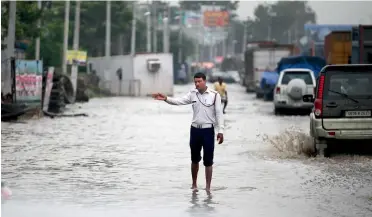  ?? — AP ?? A traffic policeman guides traffic on a waterlogge­d road in Gurgaon on Friday.