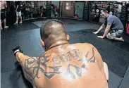  ??  ?? Perspirati­on glistens on the tattooed back of a U.S. military war veteran as he cools down in the ring.