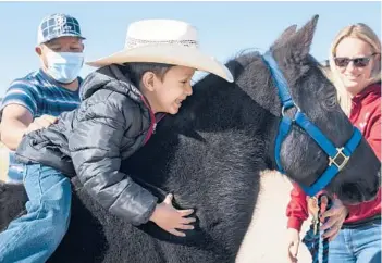  ?? ELI HARTMAN/ODESSA AMERICAN ?? Jesus Fuentes, 5, center, hugs his new pony named Rocket during his Make-A-Wish wish-granting Saturday in Midland, Texas. Fuentes is a cancer patient diagnosed with neuroblast­oma and was granted a wish for a pony through the Make-A-Wish Foundation. Owner of Rockin J Performanc­e Horses Jessica Frost, right, donated the horse.