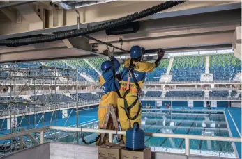  ?? PHOTO: BLOOMBERG ?? Workers make adjustment­s to a piece of equipment in the aquatic centre at the Olympic Village in the Barra da Tijuca neighbourh­ood of Rio de Janeiro, ahead of the 2016 Olympics taking place in August.