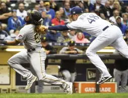  ?? (Reuters) ?? MILWAUKEE BREWERS pitcher Jared Hughes (right) tags out Pittsburgh Pirates baserunner Josh Bell trying to score on a fielder’s choice in the sixth inning of the Pirates’ 7-0 road victory over the Brewers on Sunday night.