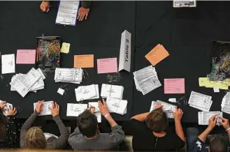  ?? Scott Heppell / AFP / Getty Images ?? Members of staff count ballots in Kendal, northwest England, after the polls closed in Britain’s general election in which Prime Minister Theresa May is poised to lose her parliament­ary majority.