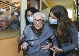  ?? ( Sergio Perez/ Reuters) ?? FLORENTINA MARTIN, a 99 year- old woman who survived coronaviru­s, is helped by her caregiver and her granddaugh­ter at the entrance of her home in Pinto, near Madrid, on Monday.