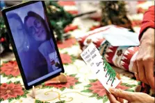  ?? (AP Photo/Luca Bruno) ?? Celestina Comotti, 81, reads a Christmas card Saturday during a video call with Alessia Mondello a donor unrelated to her who bought and sent her a Christmas present through an organizati­on dubbed Santa’s Grandchild­ren, at the Martino Zanchi nursing home in Alzano Lombardo, northern Italy.