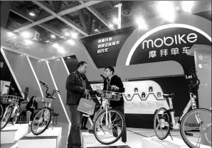  ?? LI ZHIHAO / FOR CHINA DAILY ?? An employee (right) of Mobike addresses a visitor’s inquiries at an exhibition held in Guangzhou, Guangdong province. The company ranks top in bike-sharing firms in China.