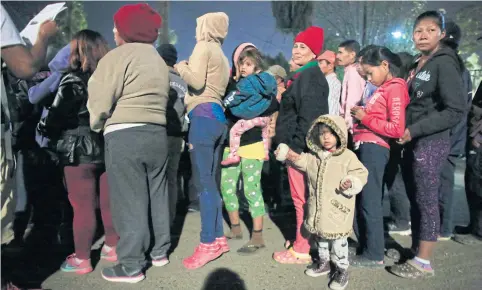  ?? AP ?? Women wait in line in hopes of receiving donated food and hygiene supplies, outside a sports complex serving as a shelter for over 5,000 migrants in Tijuana, Mexico.