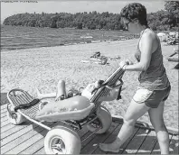  ?? SUBMITTED PHOTO/MOBI-MAT ?? A boy gets a push down a ramp to a Mobi-Mat in a floating wheelchair, also produced by the company. The Inverness County Accessibil­ity Committee hopes to use these products to make Inverness Beach fully accessible this summer.