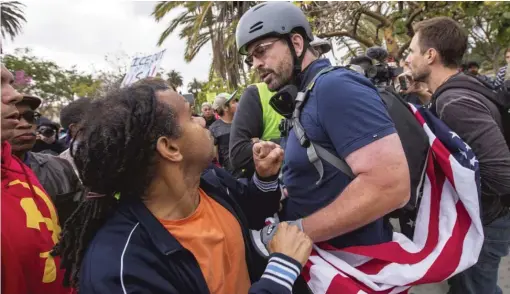  ?? DAVID MCNEW/ GETTY IMAGES ?? An anti- immigrant protester wearing a helmet and draped with an American flag fights with Latino marchers on May Day ( May 1, 2018) in Los Angeles.