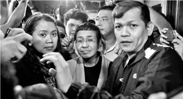  ??  ?? Ressa (centre) arrives at a regional trial court in Manila to post bail. — AFP photo